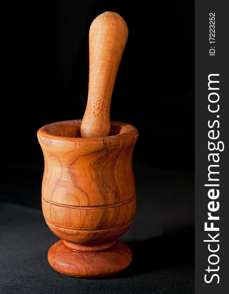 Wooden mortar and a pestle isolated on a black background. Wooden mortar and a pestle isolated on a black background.