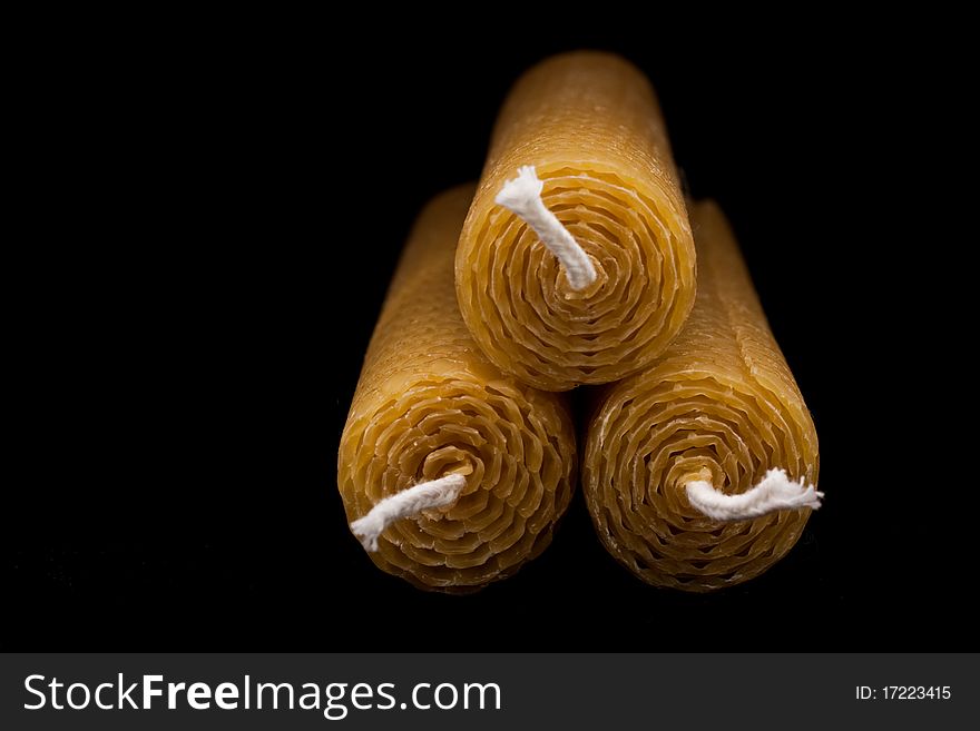 Three beeswax candles, end-on view, isolated on black with fading light