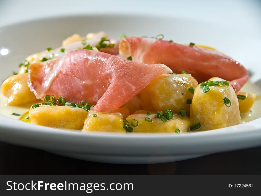 Pumpkin gnocchi with thin sliced ham and chives