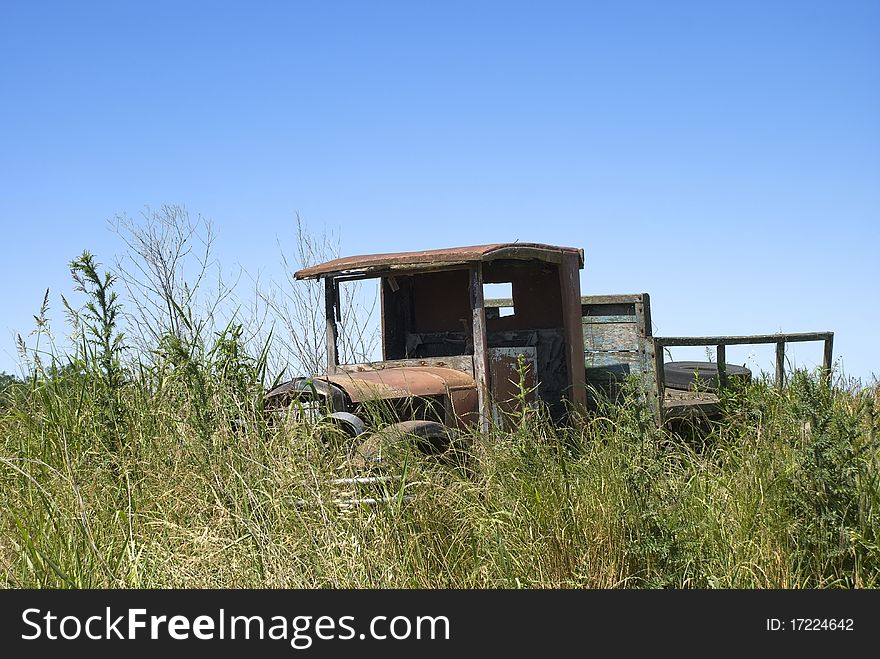 Old rusty truck, abandoned on a land full of weeds, with a blue sky on the background. Old rusty truck, abandoned on a land full of weeds, with a blue sky on the background.