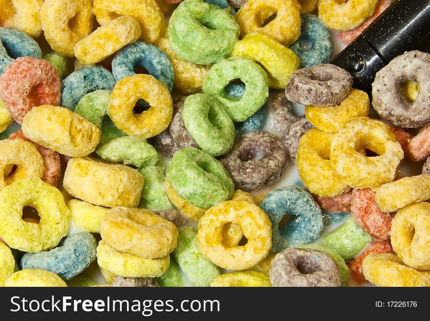 Sweet cereal rings in milk with spoon.