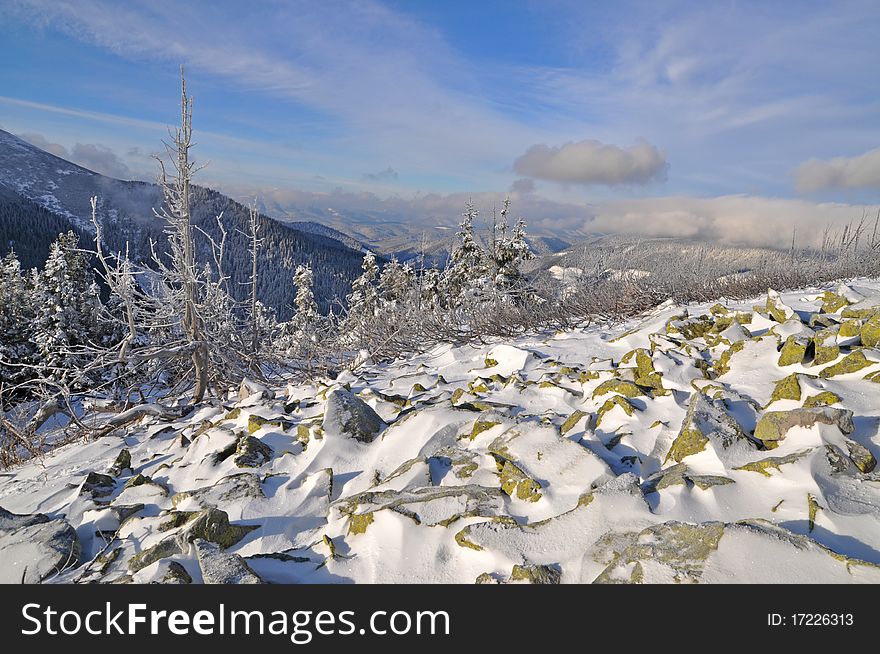 A winter stone hillside in a landscape with the dark blue sky and clouds. A winter stone hillside in a landscape with the dark blue sky and clouds