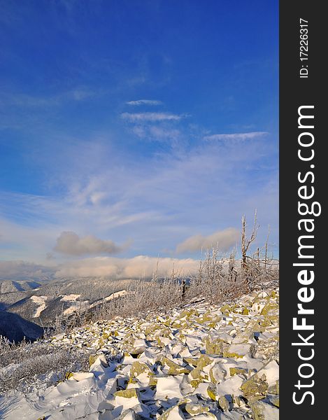 A winter stone hillside in a landscape with the dark blue sky and clouds. A winter stone hillside in a landscape with the dark blue sky and clouds