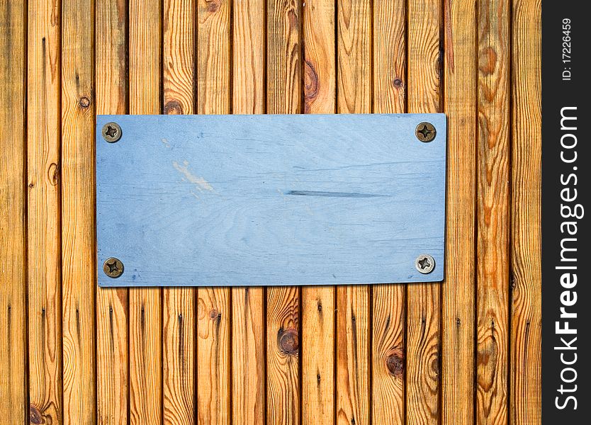 Empty plywood sign bolted to a wooden wall