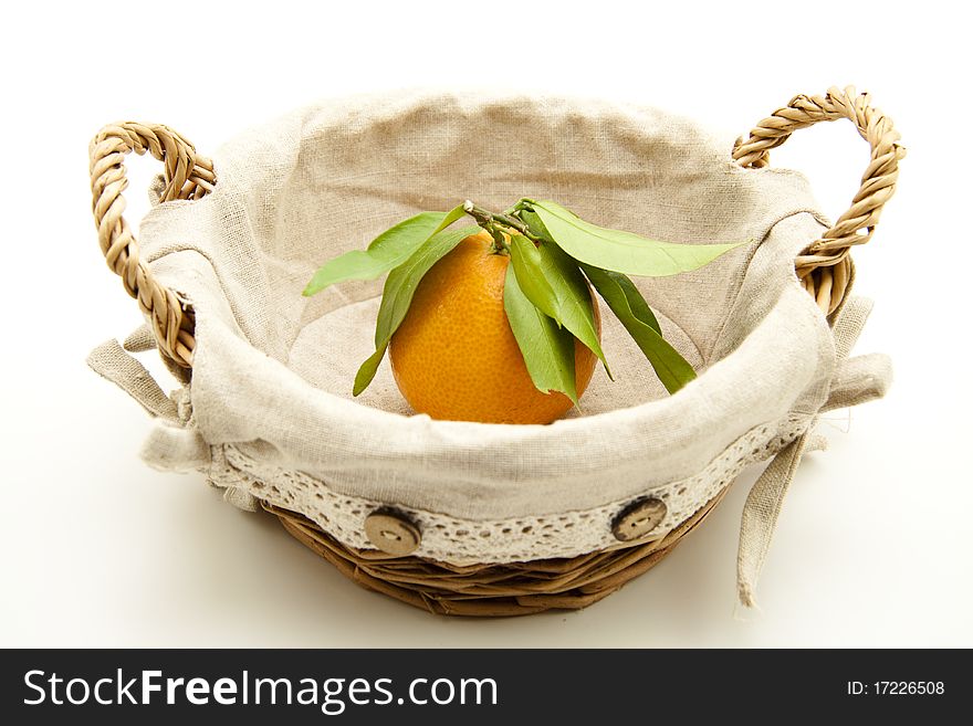 Tangerine with leaf in the basket with material