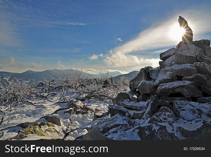 A pyramid from stones at mountain top in a winter landscape with clouds. A pyramid from stones at mountain top in a winter landscape with clouds.