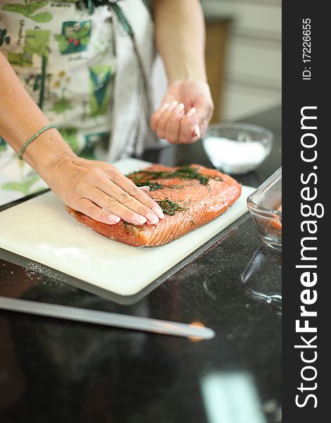 Fresh salmon fish is being marinated on chopping board. Fresh salmon fish is being marinated on chopping board