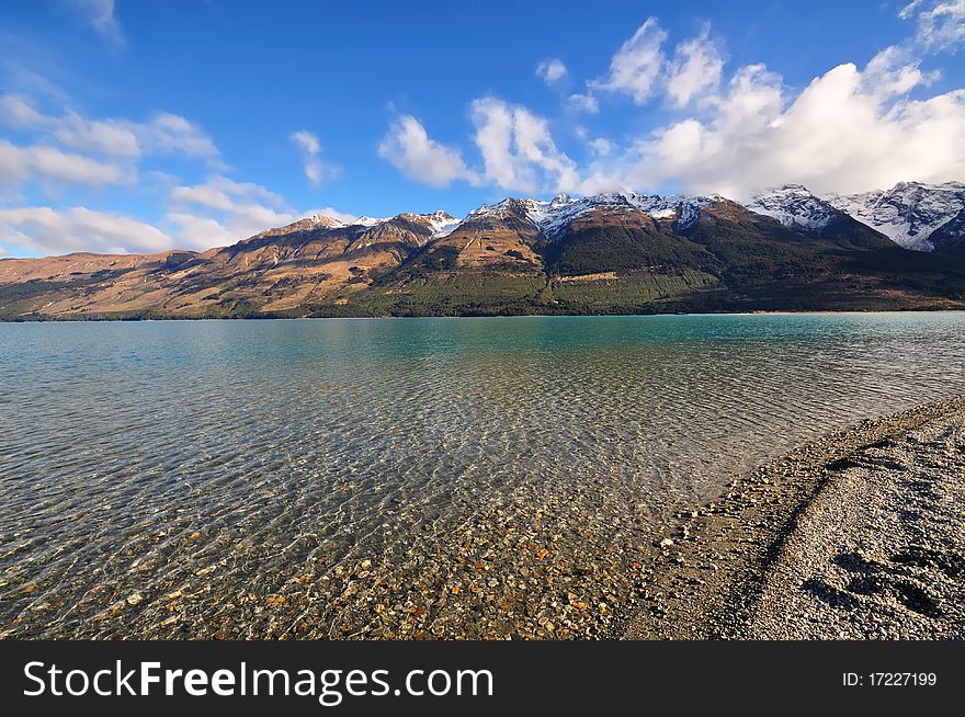 Volcanic snow-capped mountains reach toward the sky out of a crystal clear lake. Volcanic snow-capped mountains reach toward the sky out of a crystal clear lake.