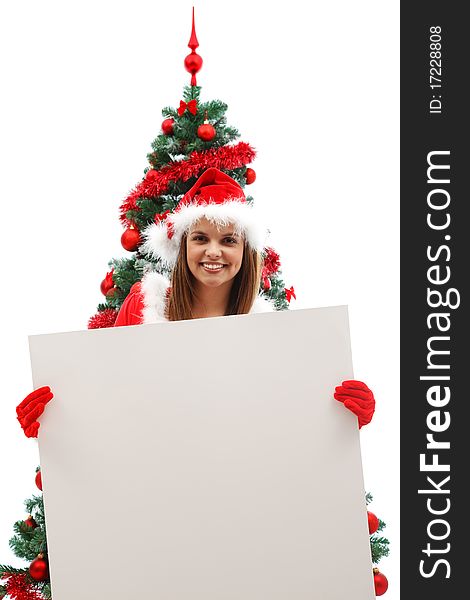 Attractive woman in santa clothes holding an empty board before the Christmas tree. Attractive woman in santa clothes holding an empty board before the Christmas tree