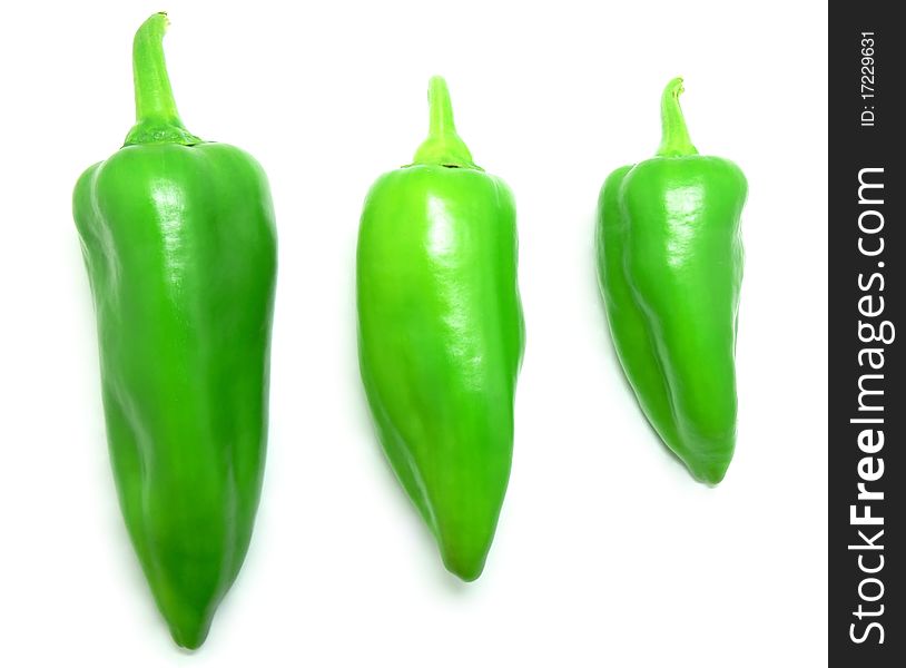 Three different sized green peppers on a white background.