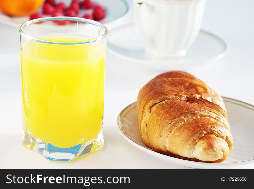 Orange juice and croissant on a bright background