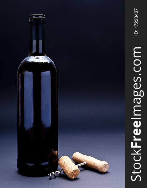 Bottle of red wine with cork and corkscrew on a dark background. Bottle of red wine with cork and corkscrew on a dark background