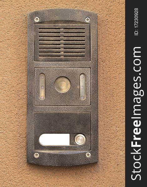 Grey metal Intercom from an apartment hanging on a beige concrete wall