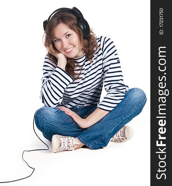 A teenager girl listening music in headphones on white background. A teenager girl listening music in headphones on white background