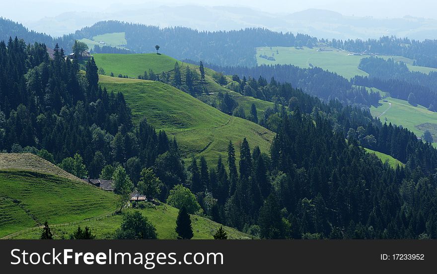The green hills of the Swiss Emmental region (foothills of the Alps) is where the famous Swiss cheese comes from. The picture is taken from an area south of the village of Sumiswald in Berne county.