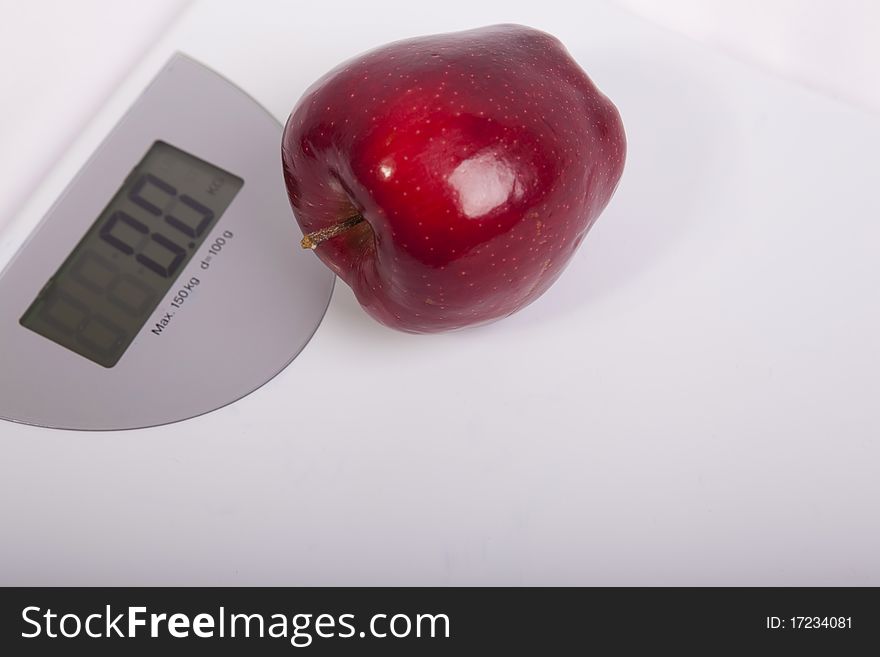 White electronic body weighing scales and a red apple.