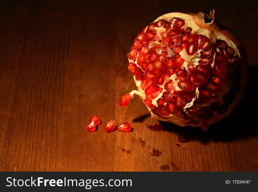 Fresh pomegranate lying on dark wooden background with lighting effect. Fresh pomegranate lying on dark wooden background with lighting effect