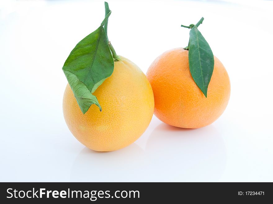 A pair of tarocco precoce oranges with leaves against a white background