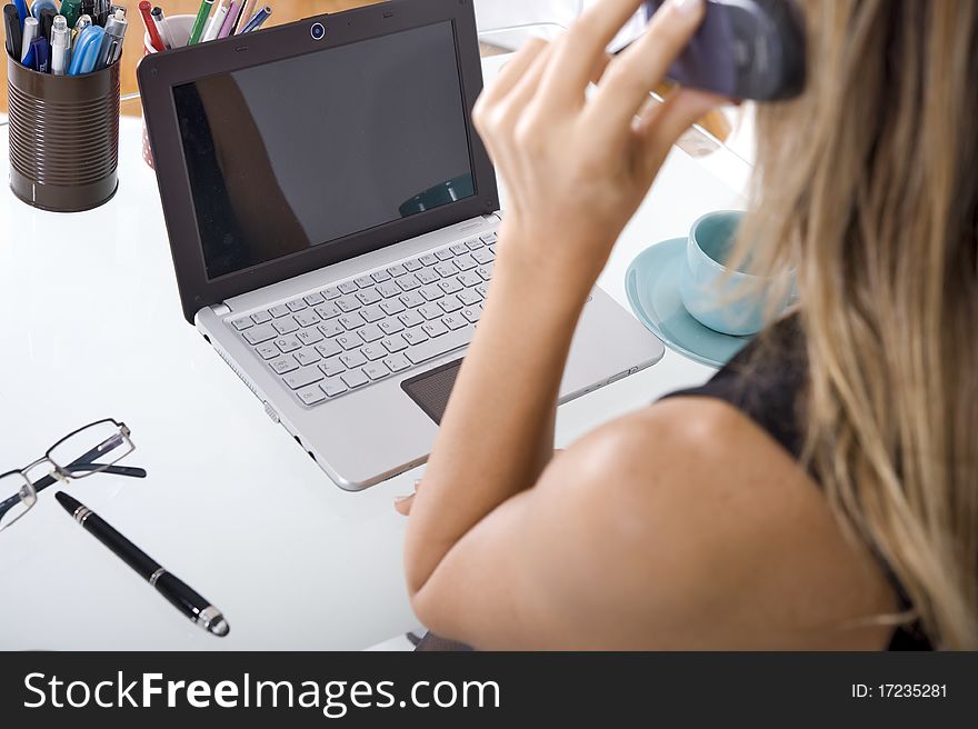 Businesswoman talking on the phone while working on laptop. Businesswoman talking on the phone while working on laptop