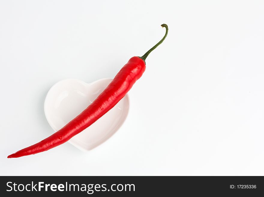 Red hot chili pepper on a heart shape saucer