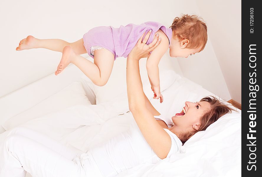 Young beautiful mother and her baby on the bed at home. Young beautiful mother and her baby on the bed at home