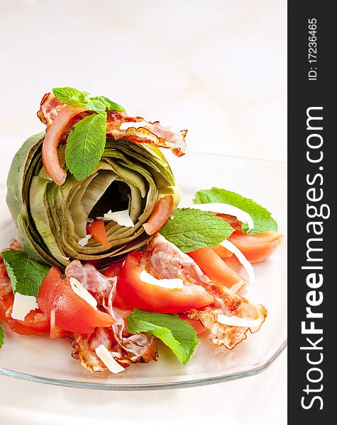 Cooked artichoke with tomatoes, parmesan cheese, pancetta, and mint