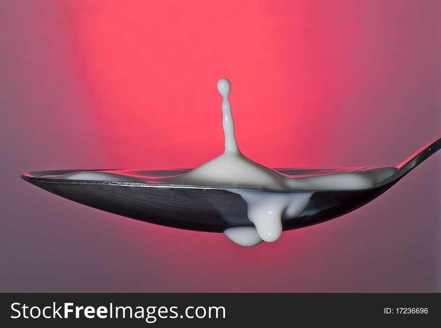 Milk in spoon with red background. Milk in spoon with red background