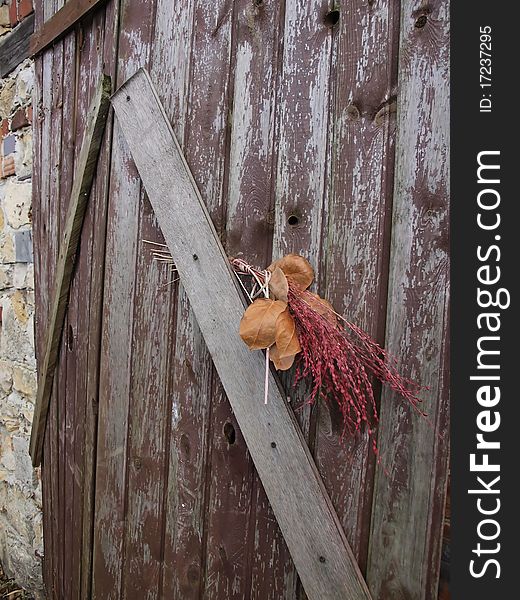 Old door with a bouquet of dried grass as decoration