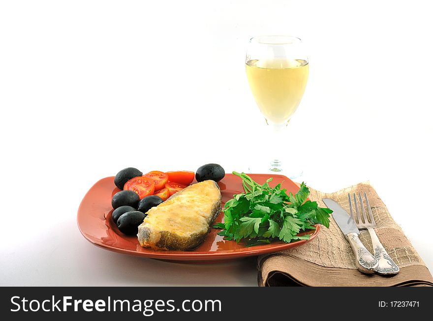 A piece of fried perch on a red plate with tomatoes and olives. A piece of fried perch on a red plate with tomatoes and olives