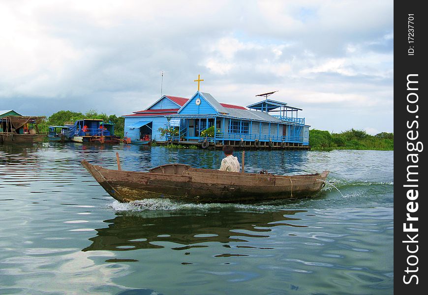 A fisherman's boat cruising in front of a floating church on the Tolen Sap Lake near Siem Reap (Cambodia)