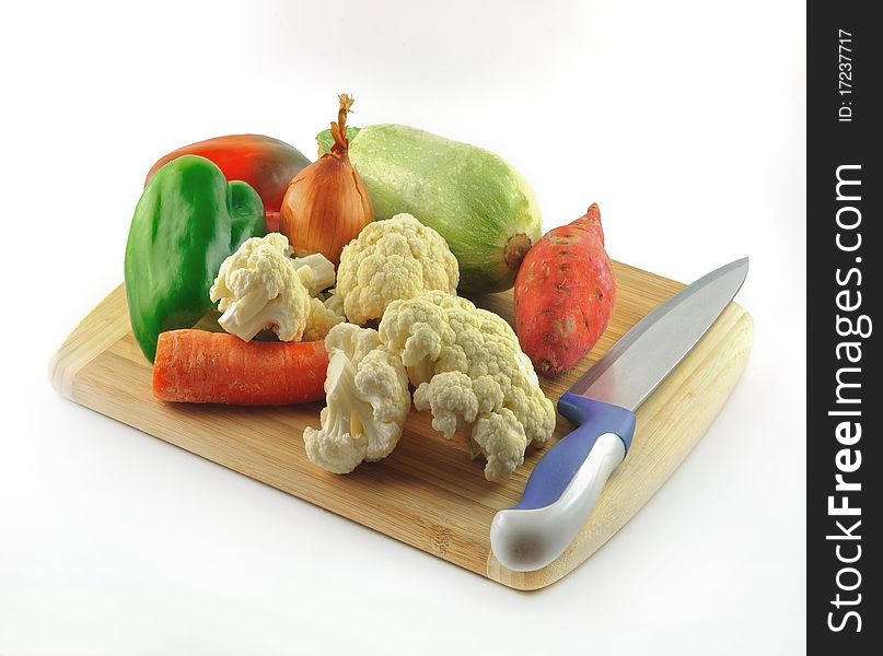 Fresh vegetables on a wooden board made of bamboo and a knife for cutting. Fresh vegetables on a wooden board made of bamboo and a knife for cutting