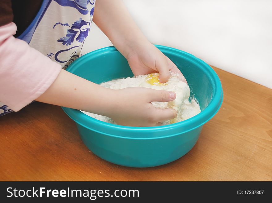 Child hands kneading a dough in a big bowl