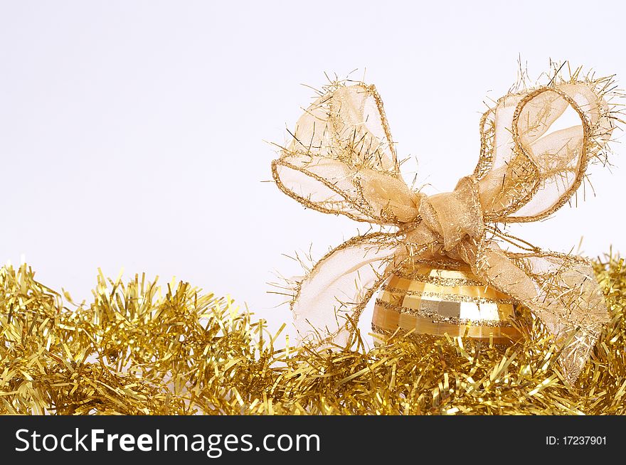 One gold Christmas bauble on yellow tinsel isolated on white background with copy space.