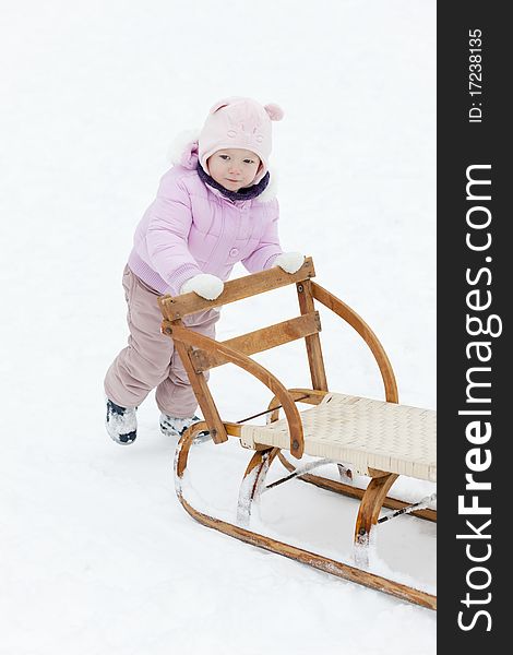 Standing little girl with a sledge