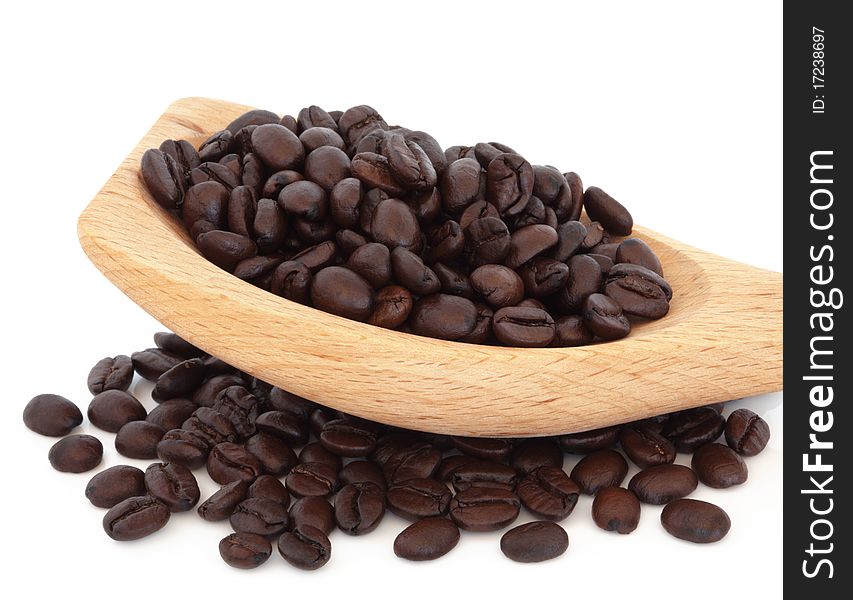 Coffee beans in a curved wooden spoon and scattered, isolated over white background.