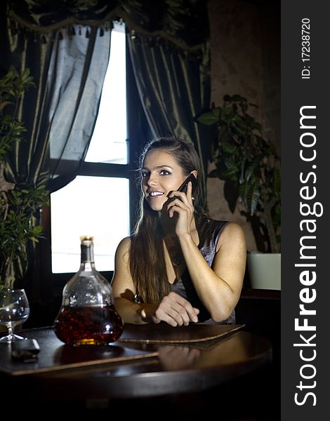 Woman sits at the table and speaks by mobile phone in vintage restaurant. Woman sits at the table and speaks by mobile phone in vintage restaurant