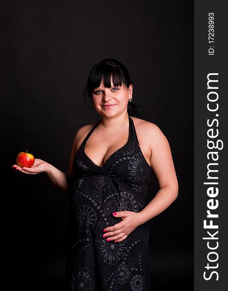 Pregnant woman in black dress with red apple