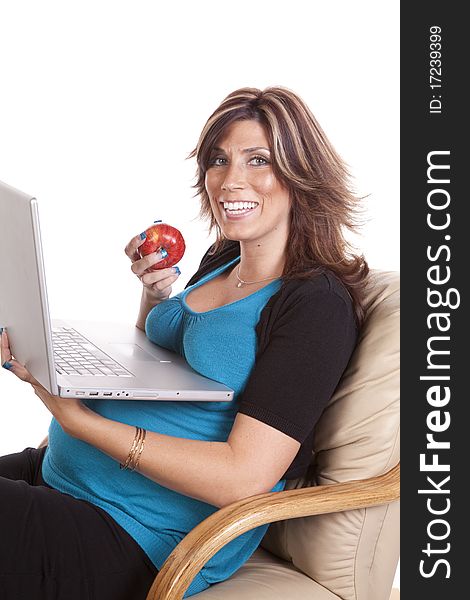 A pregnant business woman sitting and working on her lap top while eating fruit. A pregnant business woman sitting and working on her lap top while eating fruit.