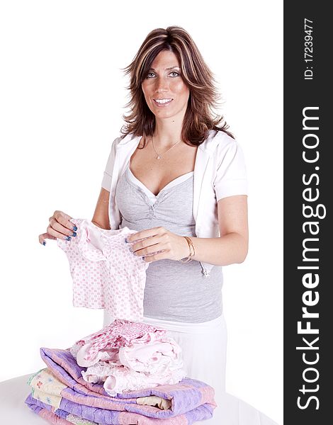 A pregnant woman folding baby clothes getting ready for the new addition to her family.