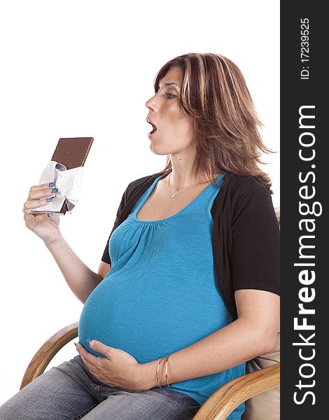 A pregnant woman sitting and enjoying a big candy bar. A pregnant woman sitting and enjoying a big candy bar.