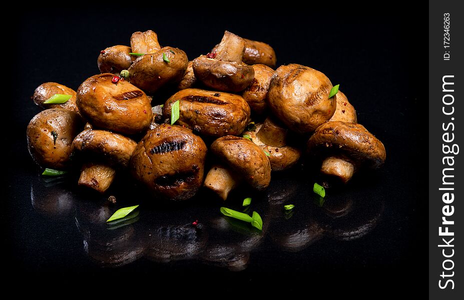 Champignon mushrooms cooked on a bonfire on a black background. Champignon mushrooms cooked on a bonfire on a black background