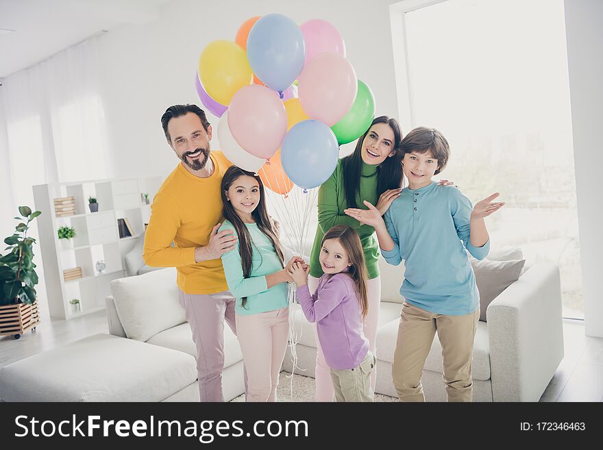 Family women anniversary celebration concept. five people daddy, mommy enjoy spend free time together three little preteen kids hold many air balls baloons in house room with couch. Family women anniversary celebration concept. five people daddy, mommy enjoy spend free time together three little preteen kids hold many air balls baloons in house room with couch