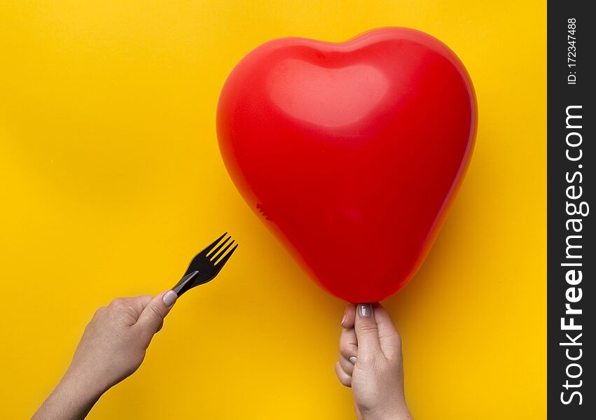 Relationship crisis, break up. Woman holding red heart balloon and pinned with scissors over yellow background