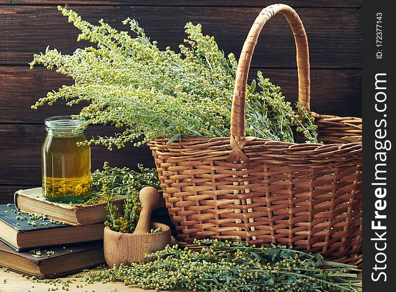 Absinth blooming herb in a wicker on wooden rustic background with bunch of sagebrush flowers