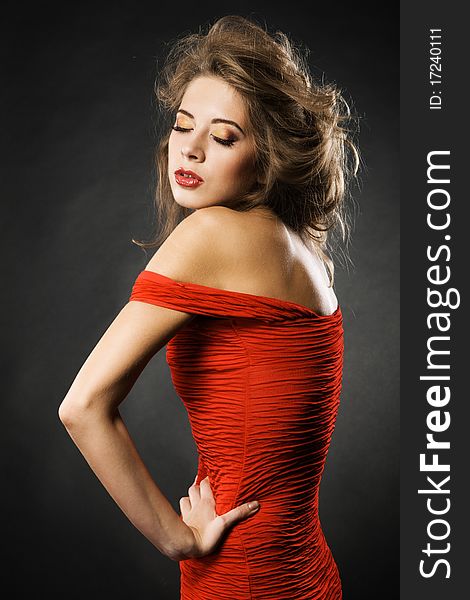 Gorgeous model in fashionable red gown, black background. Gorgeous model in fashionable red gown, black background