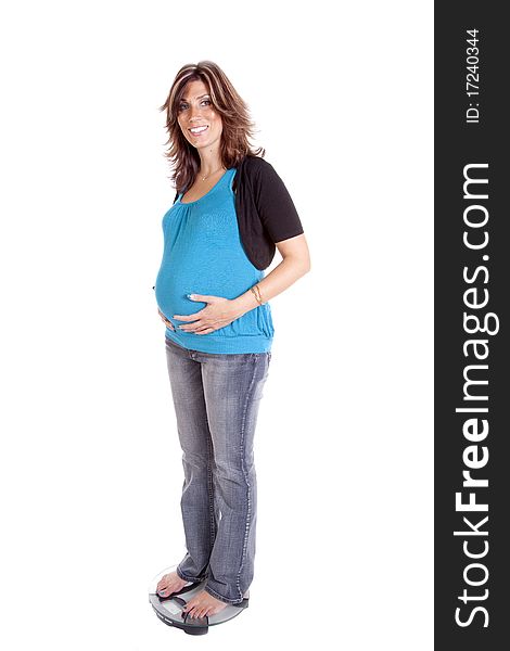 A pregnant woman standing on the weight scales holding her belly with a smile on her face. A pregnant woman standing on the weight scales holding her belly with a smile on her face.