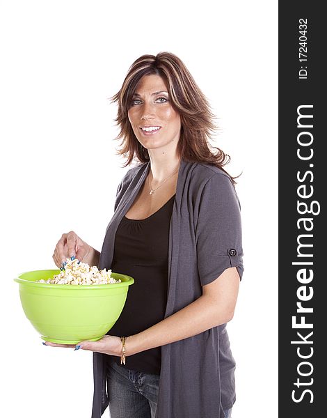 A pregnant woman standing and having a snack of popcorn in a green bowl. A pregnant woman standing and having a snack of popcorn in a green bowl.