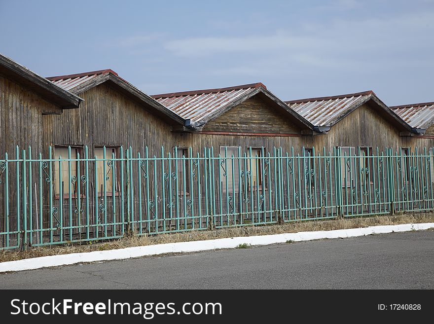 Old wooden baraks behind a green old fence