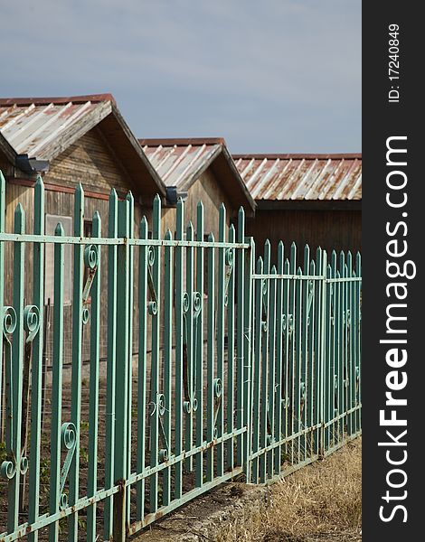 Old wooden baraks behind a green old fence