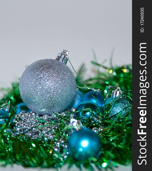 Blue, silver and green Christmas balls laying on the table, white background. Blue, silver and green Christmas balls laying on the table, white background